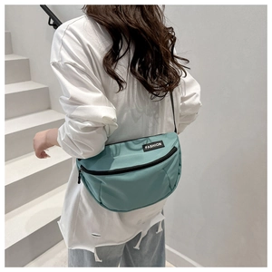 Close-up of Morandi blue nylon crossbody bag with black zipper and Fashion logo tag