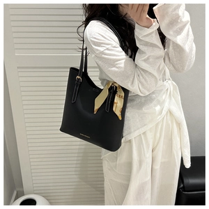 Detail of black tote bag with white stitching and decorative silk scarf on the handle