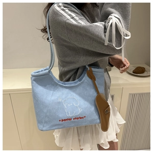 Close-up of light blue denim tote bag with cute white cartoon dog embroidery detail