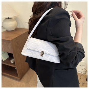 Detail of white crocodile pattern underarm bag with gold buckle on model shoulder