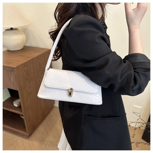 Detail of white crocodile-embossed pattern and golden buckle on elegant shoulder bag