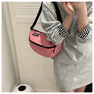 Detail of pink nylon crescent bag featuring a black zipper and fashion label tag