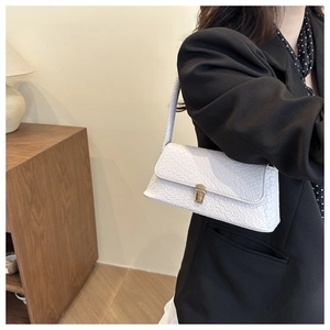 Detail shot of the white woven texture flap and golden buckle on the fashion baguette bag