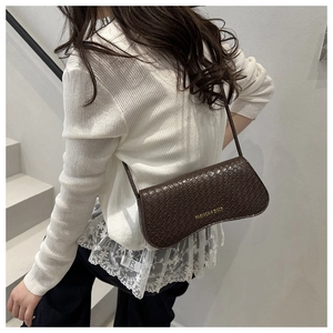 Close-up of a brown Intrecciato woven crescent shoulder bag on a model's outfit