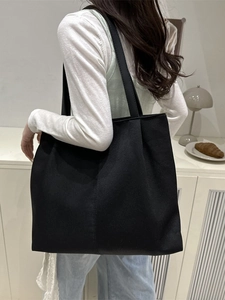 Minimalist black canvas tote bag shown from a side view on model for daily commuting