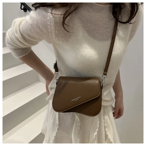 Brown PU crossbody bag featuring a unique irregular curved flap and fashion trend text
