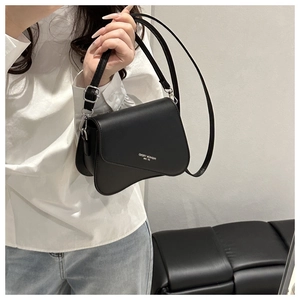 Detail of black crossbody bag with wave-shaped bottom design and silver lettering