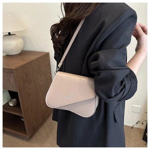 Detail of beige PU leather crossbody bag featuring unique irregular curved flap design