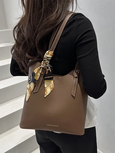 Borsa tote in pelle marrone con foulard decorativo e tracolla regolabile indossata da modella