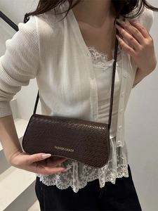 Deep brown crossbody bag with crocodile texture and gold lettering on a white background