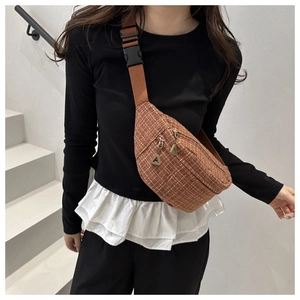 Detail of brown tweed chest bag with white cross-weave texture and adjustable strap