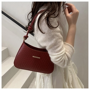 Detail view of red woven underarm bag with gold metal buckle and knotted strap design