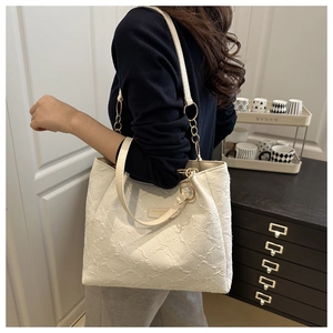Detail of off-white tote bag with jacquard texture and gold chain shoulder strap