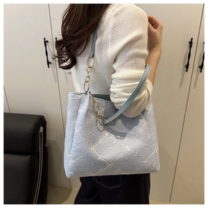 Detail of light blue tote bag with floral embroidery and chain strap on female model