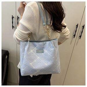 Detail of light blue tote bag featuring floral embroidery and gold chain leather strap