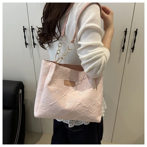 Close-up of pink tote bag with white floral embroidery and gold chain shoulder strap