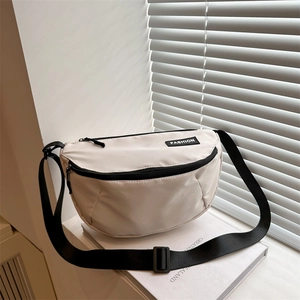 Fashionable beige crescent canvas crossbody bag with adjustable strap and fashion label