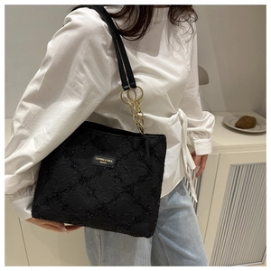 Detail of black sequined tote bag with golden chain and branded fashion metal plate