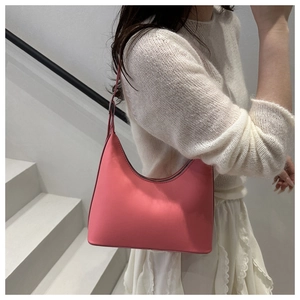 Close-up of a stylish pink hobo bag with zipper closure on a shoulder-carried model