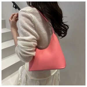 Pink minimalist leather hobo bag styled as an underarm shoulder bag on a model