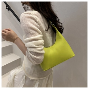 Side view of lime green leather crescent shoulder bag worn by model on stairs