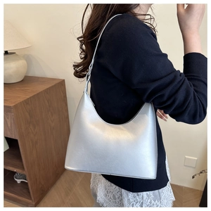 Detail of silver metallic crescent shoulder bag with minimalist leather texture and shape