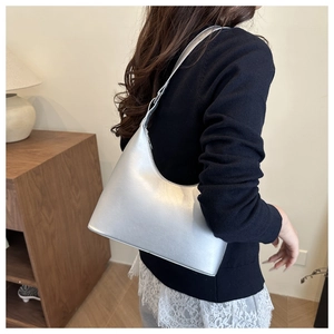 Close-up of a silver matte hobo bag with adjustable strap worn on the shoulder