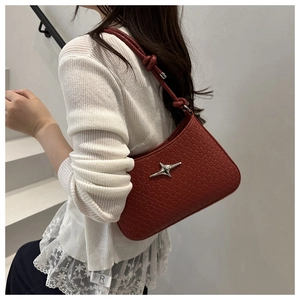 Detail of red woven leather underarm bag with silver star metal accent on shoulder strap