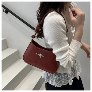 Detail of red shoulder bag with woven texture, silver star hardware and knot strap design