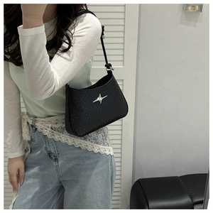 Detail of black faux-crocodile skin texture and silver star ornament on shoulder bag