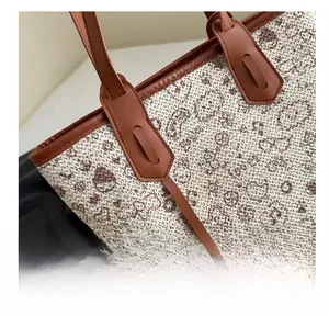Close-up of vintage woven tote bag with brown leather handles and paisley floral patterns