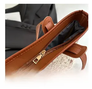 Detail of smooth gold metal zipper closure on a vintage brown leather tote bag
