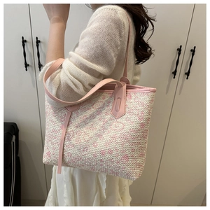 Close-up of pink and white woven tote bag with leather straps worn by a model