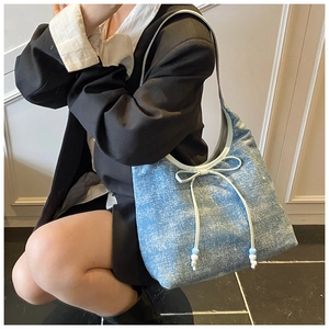 Detailed side view of blue sequin denim shoulder bag with bow and beaded charm detail