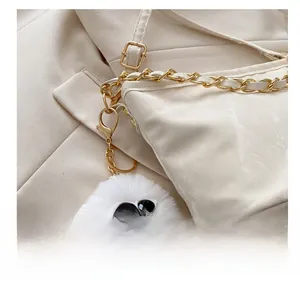 Detail of white plush bag charm with oversized sunglasses and gold metal hardware