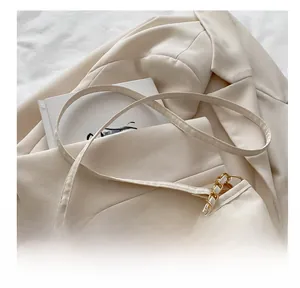 Close-up of the cream shoulder bag with adjustable leather strap and gold chain detail