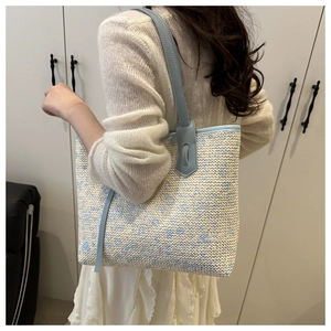 Detail of blue and beige woven tote bag showing the texture and leather shoulder strap