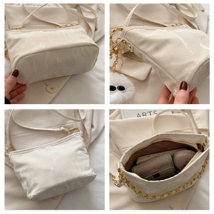 Detail view of large beige marble handbag with metal chain strap and furry pompom charm