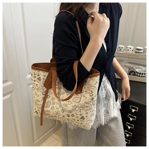 Detail of woven cream tote bag with brown leather straps and intricate pattern accents