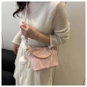 Detail of light pink bucket bag featuring pleated texture and gold chain strap handle