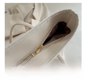 Detail of smooth gold zipper and floral embossed texture on cream tote bag