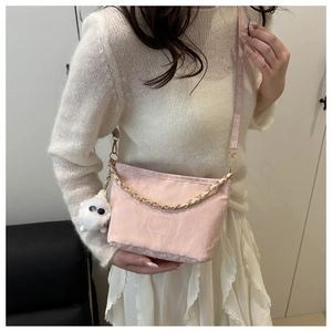 Détail du sac seau rose avec chaîne dorée et breloque peluche sur un mannequin
