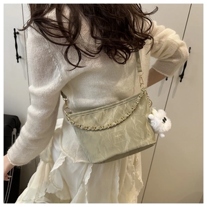 Vue détaillée du dos d'un sac seau vert clair avec chaîne dorée et peluche décorative