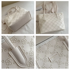 Detail of floral embossed cream tote bag with elegant brand logo and leather texture