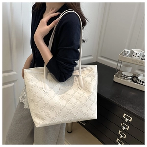 Detailed view of cream-white tote bag with floral embossing shown on a female model
