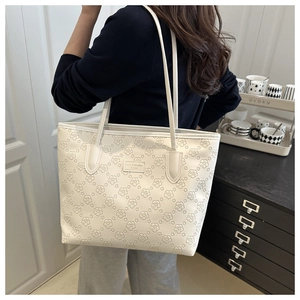 Detail of white tote bag featuring floral embossed texture and long shoulder straps