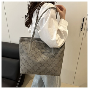 Detailed view of grey tote bag with small floral print and metallic logo on model