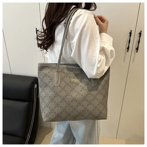 Close-up of vintage grey tote bag with floral print and gold brand plate detail