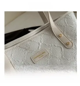 Macro detail of quilted texture with floral embroidery and gold rivets on tote bag
