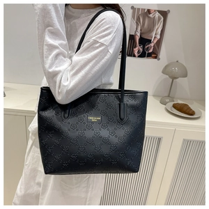 Detail of black tote bag with 3D floral embossing and gold metal logo plaque